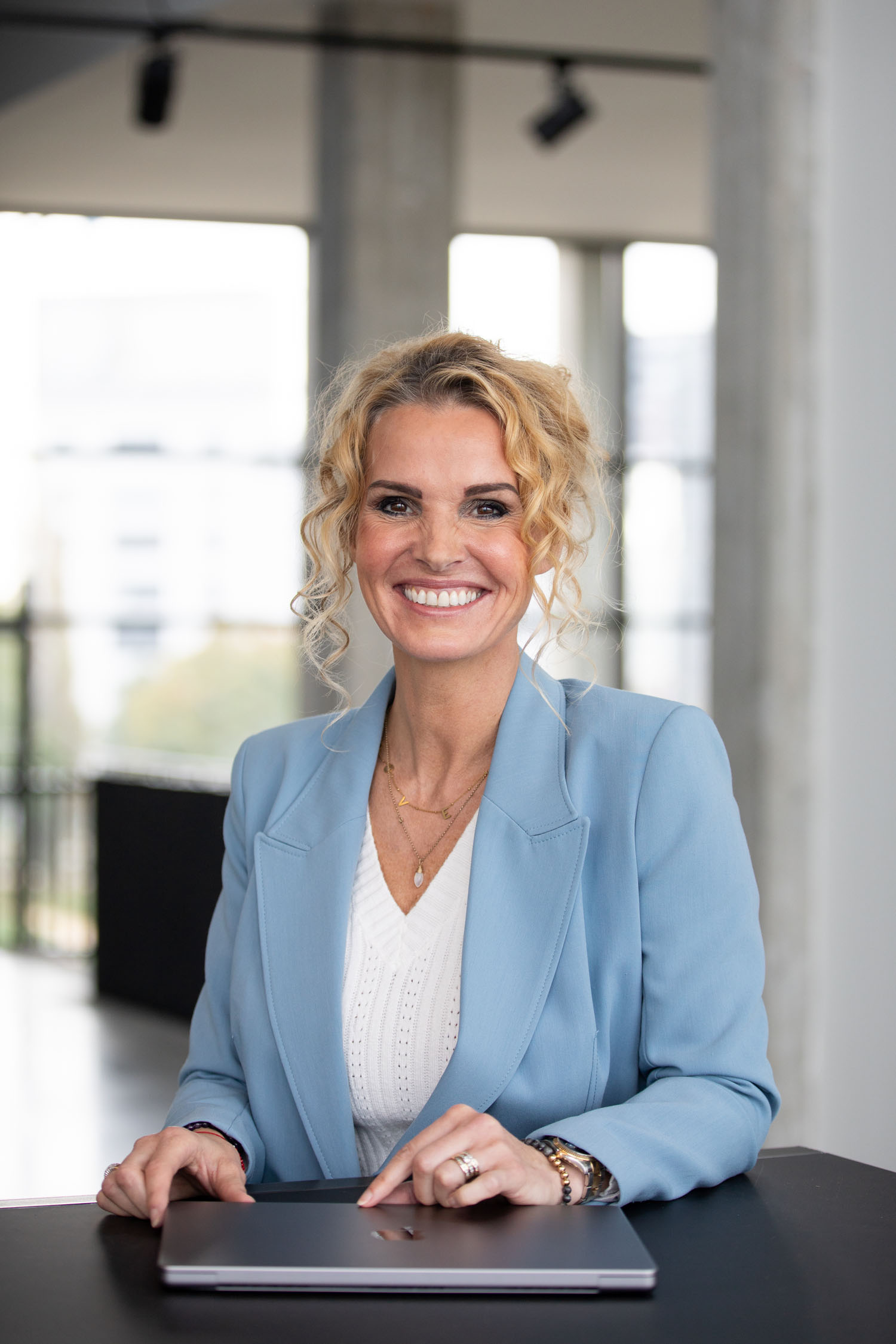 Petra van de Laarschot in een lichtblauw pak aan tafel met haar laptop