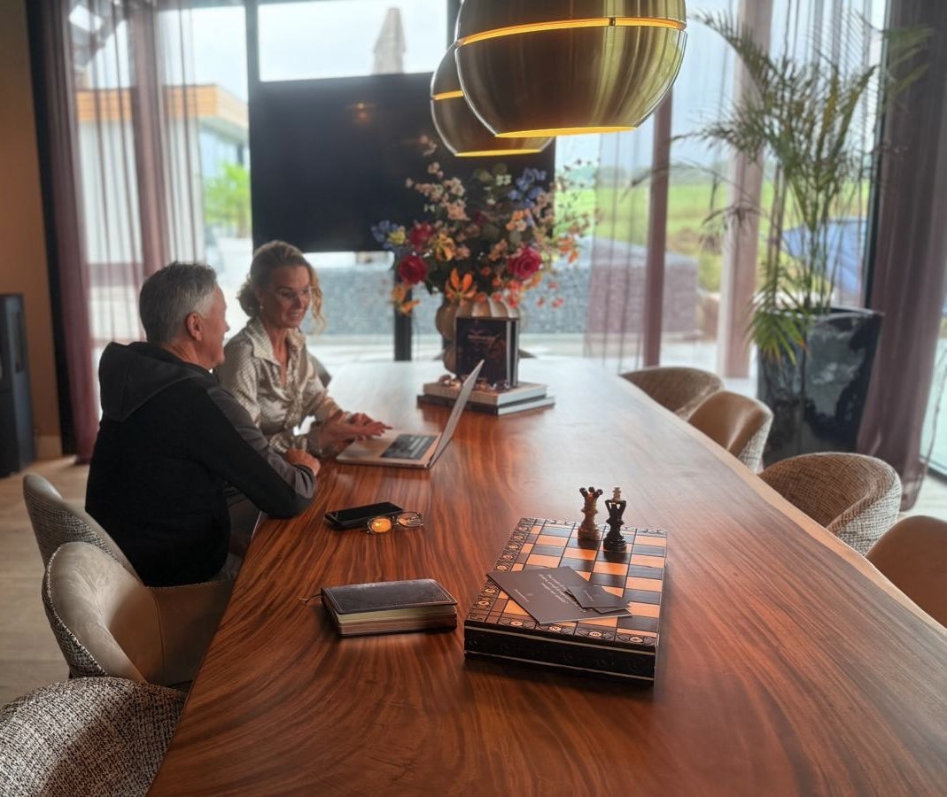 Petra van de Laarschot en een cliënt kijken samen naar de laptop aan tafel in haar kantoor in Rossum